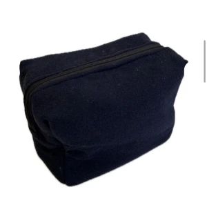 Svart necessär med dragkedja - Praktisk svart necessär med dragkedja, perfekt för att organisera dina toalettartiklar. Den kompakta designen gör den lätt att packa ner i resväskan eller gymväskan. Den har även en vaxduk på insidan för att förenkla rengöring vid smuts och fläckar!