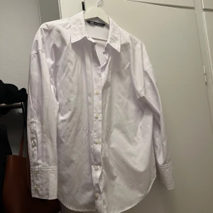 Vit skjorta från Zara - Säljer en klassisk vit skjorta från Zara. Skjortan har en normal passform med långa ärmar och knappar 