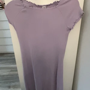 Ljuslila ribbad klänning från Lindex - Säljer en ljuslila ribbad klänning från Lindex. Klänningen har korta ärmar och en fin volangdetalj vid halsringningen. Perfekt för en avslappnad och stilren look. Storleken passar folk som är 158-170cm långa💜