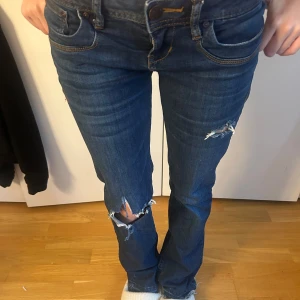 Blå jeans med hål från LTB - Snygga blå jeans från LTB med slitningar på knäna och låren. De har en lågmidjad passform. Väldigt trendiga och storlek 25/32