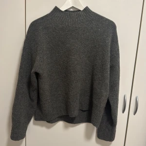 Grå stickad tröja - Säljer en mysig grå stickad tröja med ribbad krage och muddar.