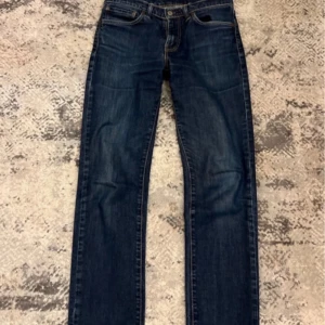 Mörkblå jeans från Levi's - Säljer ett par klassiska mörkblå jeans från Levi's. De har en rak passform och är tillverkade i slitstarkt denim. Perfekta för en avslappnad stil. Levi's-logga på baksidan och femficksdesign.