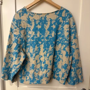 Beige och blå mönstrad tröja - Säljer en unik tröja med ett abstrakt mönster i beige och blått. Tröjan har en lös passform och långa ärmar, perfekt för en avslappnad stil. Den är tillverkad i ett mjukt material som känns skönt mot huden.