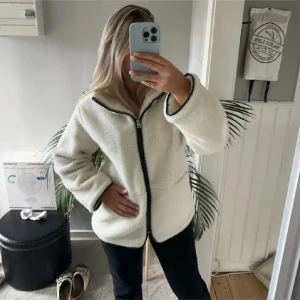 Vit teddyjacka med dragkedja - (Lånade bilder från hon ja köpte av)Mysig vit teddyjacka med svart dragkedja. Perfekt för kyliga dagar med sin fluffiga och varma design. Jackan har långa ärmar och en bekväm passform som gör den lätt att bära över andra kläder.köpte här på plick för ett tag sen, men säljer då ja har en liknande.