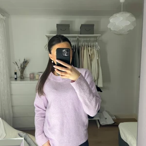 Ljuslila stickad tröja - Säljer en mysig ljuslila stickad tröja med rund hals och långa ärmar. Perfekt för kyligare dagar och ger en stilren look. Passar bra till jeans eller kjol för en avslappnad stil.
