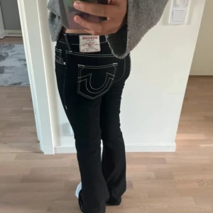 True religion jeans  - Snygga svarta bootcut jeans från True Religion med kontrasterande vita sömmar. Byxorna har en lågmidjad passform och klassiska femficksdetaljer. Perfekta för en stilren look.(köpt på butik i usa) 
