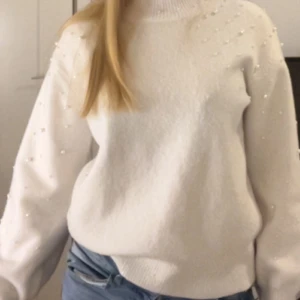 Vit stickad tröja med pärlor - Säljer en stilren vit stickad tröja dekorerad med pärlor. Tröjan har långa ärmar och en hög krage som ger en mysig känsla. Perfekt för kyligare dagar. Tröjan är från kapphal i storlek S. Kontakta vid minsta fundering💕💕