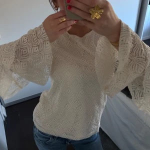 Vit spetsblus med vida ärmar - Säljer en elegant vit spetsblus med vackert mönster och vida ärmar. Perfekt för en stilren look. Blusen har en normal passform och är tillverkad i ett mjukt material som ger en bekväm känsla.