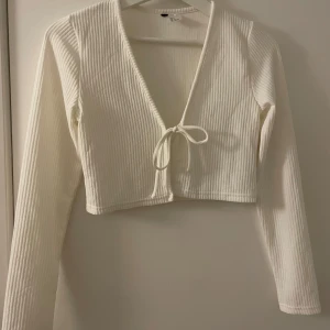 Vit ribbad kofta/bolero - Kort kofta/bolero från H&M med knytning framtill. Mycket stretch. Ribbad 