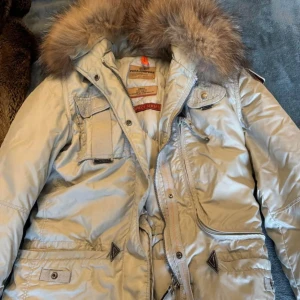 Beige vinterjacka från Parajumpers - Säljer en dam storlek s beige Parajumper ord pris cirka 9800 kr. Jackan har ett litet hål i fickan men inget som stör går att sy upp.  Som ni kan se så har det släppt lite blå färg av regnet. Detta är väldigt osynligt och syns knappt, aldrig testat och tvätta jackan , går kanske bort.  ( därav billigt pris )
