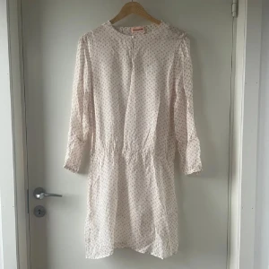 Vit och rosa klänning från Custommade - Charmig vit klänning med rosa prickar från Custommade. Underklänning medföljer. Perfekt över bikini eller sommen fin sommarklänning