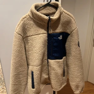 Beige kofta från The North Face - Skön beige kofta från The North Face med blå detaljer. Storlek: L