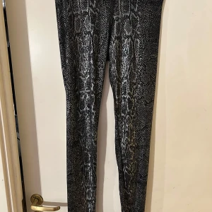 Ormmönstrade leggings - Snygga ormmönstrade leggings i svart och grått. Perfekta för en trendig look med en tight passform. De är stretchiga och bekväma, vilket gör dem idealiska för både vardag och träning.