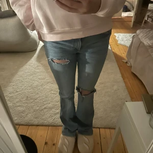 Blå jeans med slitningar lågmidjade - Snygga blå jeans med slitningar på knäna. Perfekta för en avslappnad stil. De har en klassisk passform och är tillverkade i ett bekvämt denimtyg. Midja: 35 längd: 84