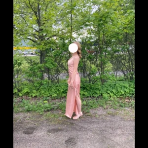 Fin balklänning tyvärr så har sömnen vid dragkedjan gått upp lite längst upp men inget som påverkar dragkedjans funktion men det blir en liten öppning som på bilden - Elegant champagnefärgad långklänning från Sisters Point i satin. Klänningen har en draperad framsida och smala axelband. Den är försedd med en diskret dragkedja på sidan för enkel påklädning.