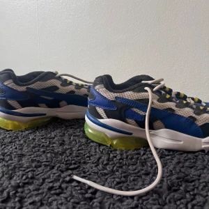 Puma sneakers  - Snygga Puma sneakers i blått, svart och vitt med detaljer i gult. Skorna har en sportig design med snörning och en väldigt bekväm sula. Knappt använda!