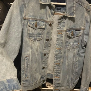 Ljusblå jeansjacka från zara - Snygg ljusblå jeansjacka från zara. Jackan har klassisk design med knappar framtill och två bröstfickor med lock. Perfekt för en avslappnad stil.