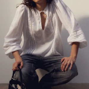 Vit blus med detaljer - Säljer denna vita blusen från hm dåden inte kommer till användning :( Flowig blus med knyte och detaljer fram till, samt på armarna🩷Perfekt till våren!!🌸🌞🍀