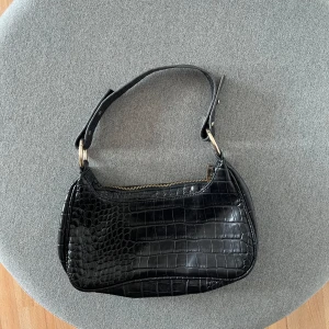 Svart väska - Skitsnygg väska ifrån nelly, den är svart med guldiga detaljer. Säljer då den inte längre kommer till användning💕💕