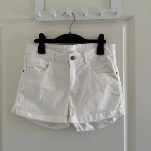Vita shorts från H&M - Säljer ett par vita shorts från H&M i storlek 170. De är bekväma med klassisk design med knapp och dragkedja framtill. Perfekta för sommardagar!