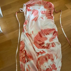 Kort klänning med snören  - En vit klänning med ombre av orange, aldrig använd, genomskinlig och ganska kort 