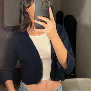 Svart bolerotopp - Säljer en stilren marinblå bolerotopp med trekvartsärm. Perfekt att ha över en topp eller klänning för en extra touch. Den är croppad och passar bra till både vardag och fest!!