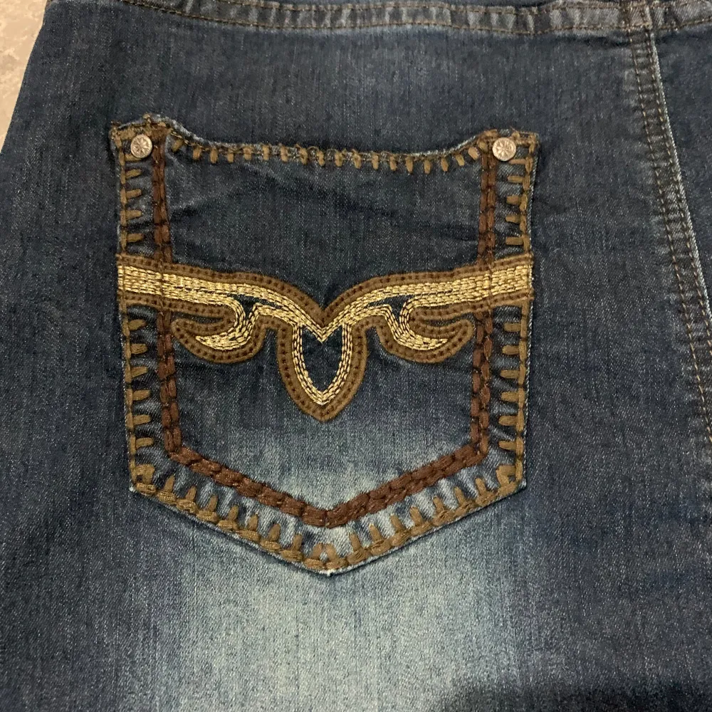 Säljer en snygg jeanskjol i mörkblå denim med coola broderade detaljer på bakfickorna. Är helt ny men utan prislappen. Kjolar.