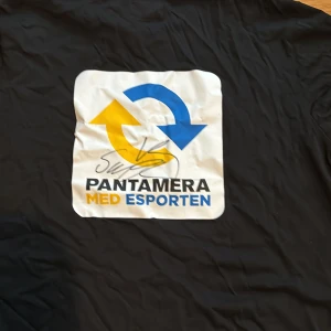 Signerad SampeV2 T-shirt  - Säljer en svart t-shirt från Cottover i storlek L signerad av Sampe V2. Den har ett coolt Pantamera med Esporten-tryck i blått och gult på framsidan. Perfekt för dig som gillar esport och vill ha en bekväm t-shirt i bomull. Den är i nyskick och redo för nya äventyr!
