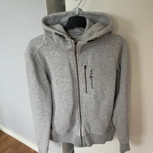Sail racing zip hoodie - Grå zip hoodie från sail racing i storlek S. Den har en lite fläck på ärmen, går säkert bort med lite vanish, men jag har inte orkat. Lite blekt vid dragkedjan och därav det billiga priset