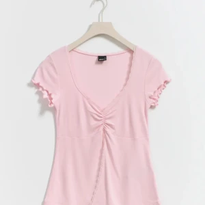 Rosa topp med volangdetaljer - Söt rosa topp med korta ärmar och volangdetaljer vid ärmslut och hals. Toppen har en v-ringad design med en snygg rynkning framtill som ger en feminin touch. Perfekt för en somrig look! Helt i nyskick! Skriv om ni vill se bilder ifrån min topp!🥰