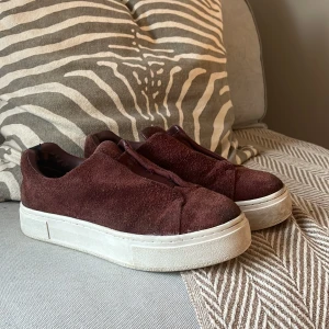 Eytys Burgundy sneakers i mocka - Säljer ett par snygga Eytys sneakers i mocka i färgen burgundy med en tjock vit sula. De har en stilren design utan snörning och är perfekta för både vardag och fest. Skorna är i bra skick med lite slitage på insidan. Passar perfekt till höstoutfits!