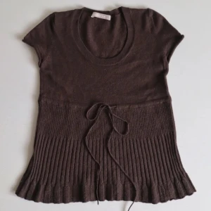 Brun stickad topp med knytband - Säljer en superfin brun stickad topp med korta ärmar och knytband i midjan. Den har en ribbad nederdel som ger en snygg passform. Perfekt för både vardag och fest!