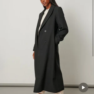 Svart kappa - Snygg och stilren svart kappa i lång modell. Perfekt för höst och vinter. Den har en lite figursydd passform och knappar framtill. Köpt från NA-KD för 1199, snålt använd och i väldigt bra skick! 