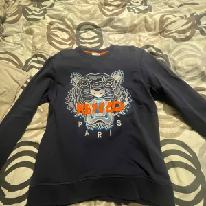 Svart sweatshirt från Kenzo med tigerbroderi - Säljer en mörkblå Kenzo sweatshirt i mycket bra skick. Den har ett coolt tigerbroderi i silver och blått med orange detaljer på framsidan. Perfekt för höst och vår! Passar både till vardags och fest. 🐯✨stor i storleken passar S och lite större 