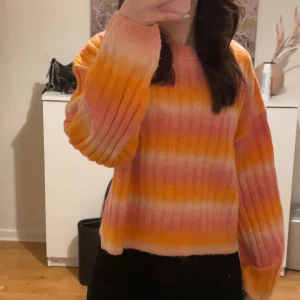 färgglad stickad tröja  - Säljer en superfin stickad tröja i rosa, orange och vit. Den har en loose passform och långa ärmar, perfekt för både vår och höst. Har bara använt ett fåtal gånger, så är i mycket bra skick! 💕