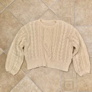 Krämvit kabelstickad tjocktröja - Krämvit kabelstickad tjocktröja i lätt Croppad passform, stl S. tröjan är i fint skick men lite lätt noppig. Klicka gärna på köp nu och meddela för eventuella frågor. :)
