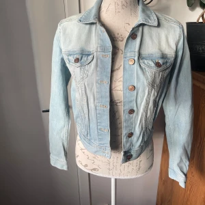 Jeansjacka Divided  - Snygg jeansjacka från H&M i stl 38. Ljusblå lite sliten modell. Fint skick.