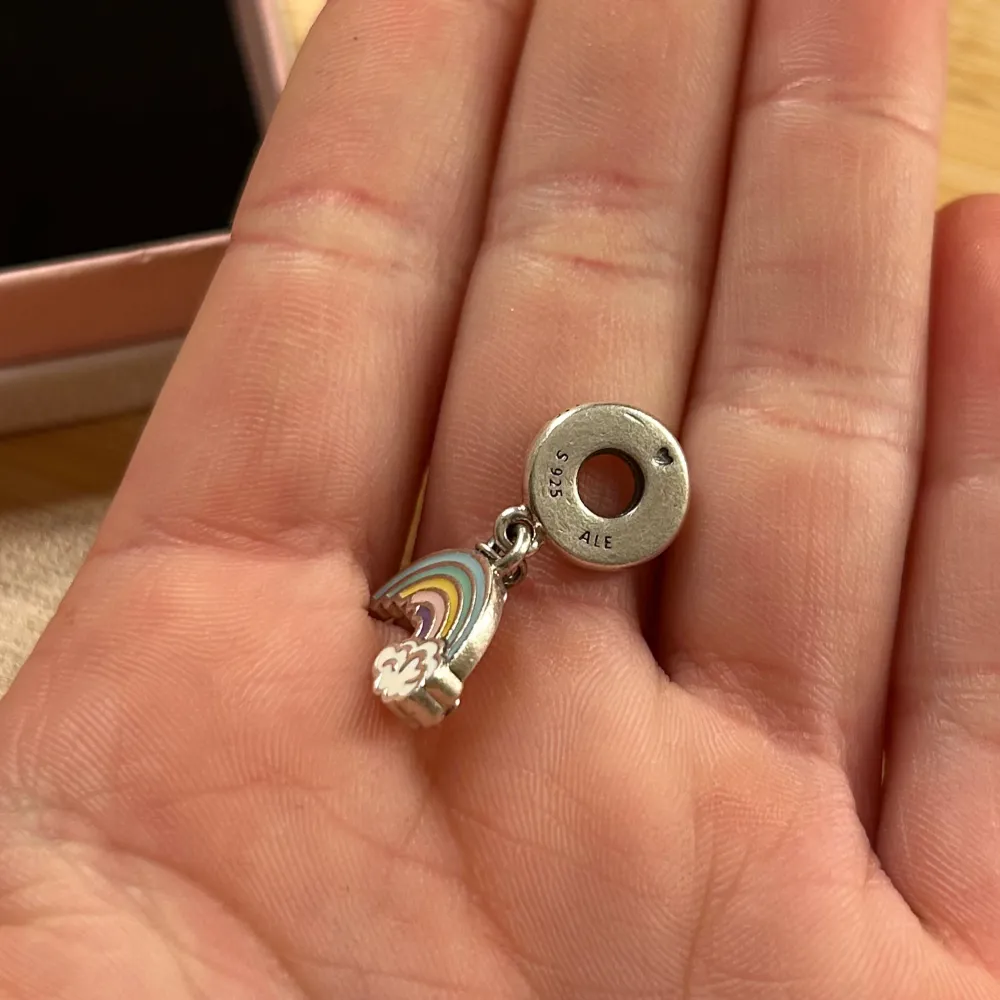 Säljer en superfin regnbågsberlock från Pandora i silver. Den har en söt regnbåge med moln i olika färger som hänger från en rund ögla. Perfekt för att ge lite färg och glädje till ditt armband eller halsband! 🌈. Accessoarer.