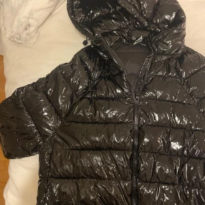 Svart glansig jacka - Säljer en svart glansig pufferjacka med huva från Zara, passade tyvärr inte mig som jag hade tänkt,  har knappar längst ner på ärmarna som går att öppna så att de ser ut som en slits🤍🤍