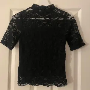 Säljer en elegant svart spetsblus från H&M i storlek XS. Blusen har korta ärmar och ett blommigt mönster. Perfekt för festliga tillfällen eller till vardags