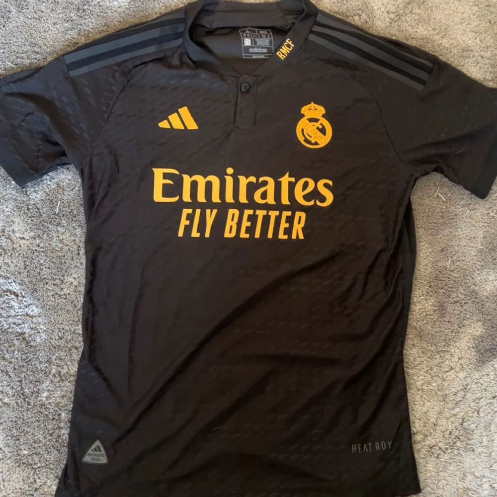 Säljer en snygg svart fotbollströja från Real Madrid. Tröjan har korta ärmar och är i nyskick. Storleken är L men passar M lika bra . T-shirts.