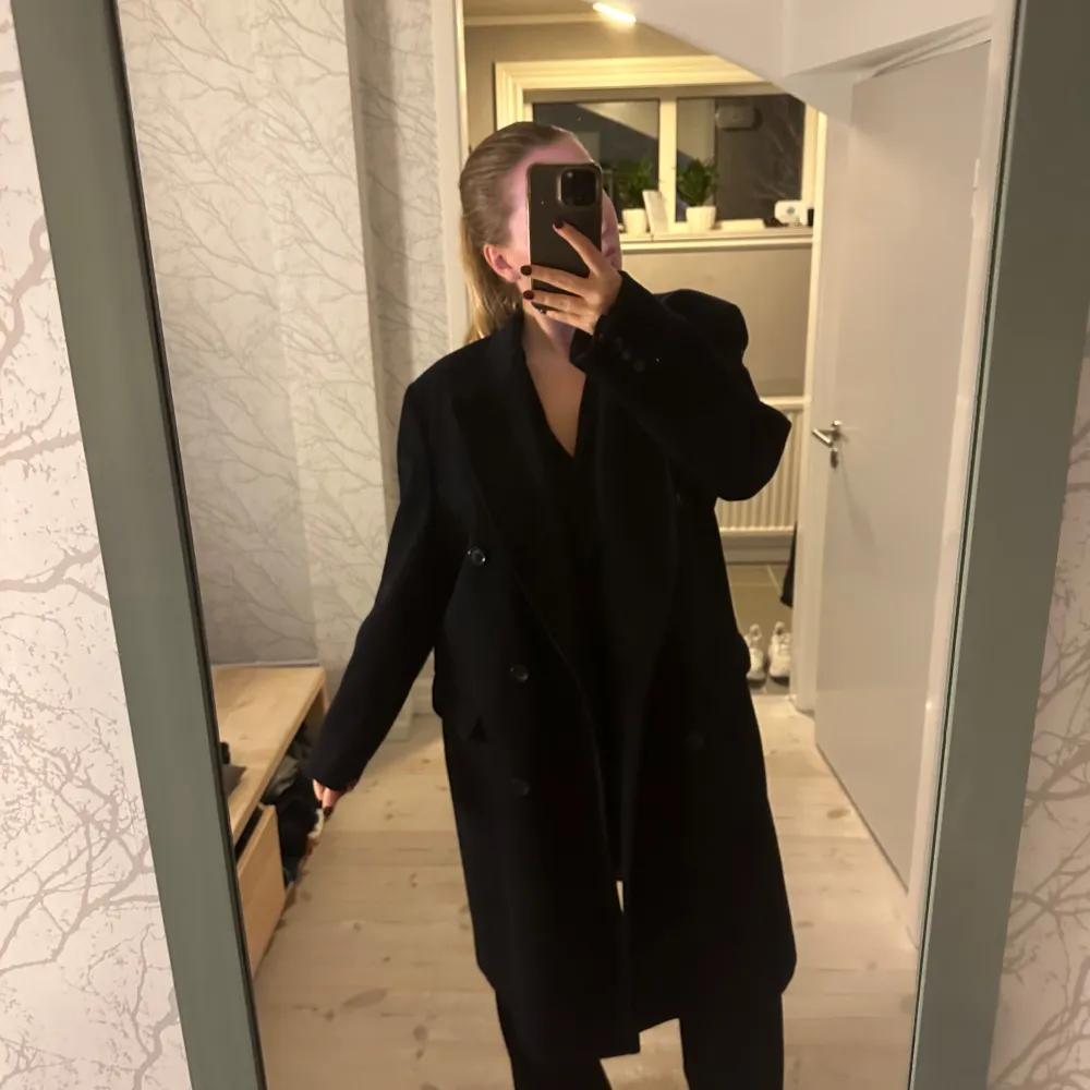 Säljer en elegant svart kappa från Yves Saint Laurent. Den har en klassisk design med dubbelknäppning och långa ärmar. Perfekt för höst och vinter, och ger en stilren look till alla tillfällen. Kappan är i mycket bra skick och passar perfekt för både vardag och fest.. Jackor.