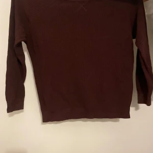 vinröd stickad tröja - Säljer en mysig vinröd stickad tröja köpt i london  i bra skick. Perfekt för höst och vinter med sin varma och bekväma design. Tröjan har långa ärmar och en enkel stil som passar till det mesta. Perfekt för att hålla sig varm under kyliga dagar! Kontakta för fler bilder, lägre pris vid direkt köp