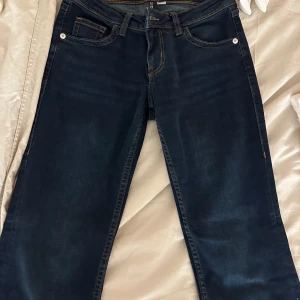Mörkblå jeans från H&M Divided - Säljer ett par mörkblå jeans från H&M Divided i storlek M. De har en klassisk femficksdesign med snygga orangea sömmar på bakfickorna. Perfekta för både vardag och fest! 🕺