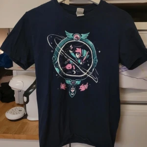 Mörkblå zelda t-shirt  - Säljer en mörkblå t-shirt med ett coolt zelda mottiv i  rosa och grönt. T-shirten har korta ärmar och ett unikt tryck med en astronaut och grisar i rymden. Perfekt för dig som gillar unika och roliga tryck!
