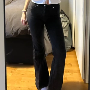 Svarta bootcut jeans - Snygga svarta bootcut jeans med hög midja. Perfekta för en stilren look. De har en klassisk design med knappar och dragkedja framtill.