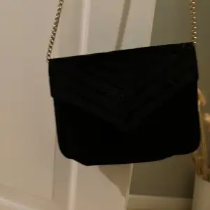 Snygg svart axelväska med en elegant kedja som axelrem. . Väskan har en praktisk storlek för att bära med det viktigaste.🩷