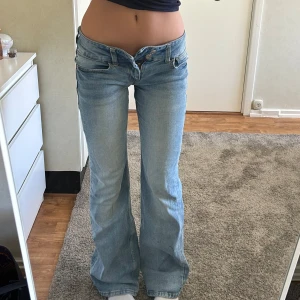 lågmidjade jeans - Ljusblåa lågmidjade bootcuts! Jeansen är lite slitna på ändarna, det finns även några fläckar fast de är inte så synliga. Knapparna funkar fint, de passar bara inte mig. Jeansen är ganska använda så priset kan diskuteras💓 Midjemått: 35cm tvärs över. Innerbenslängs: 80cm.