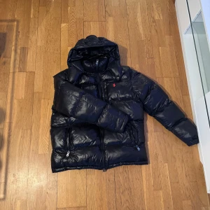 Vinterjacka Polo  Ralph lauren  - Säljer en svart dunjacka med huva och dragkedja. Jackan har långa ärmar och två fickor med dragkedjor. Perfekt för kyliga dagar. Nypris ca 4000kr mitt pris 2500