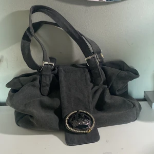 Grå axelväska med krona - Snygg grå axelväska med diamant detaljer, några diamanter saknas (se bild). Annars väldigt bra skick. Skriv vid frågor 